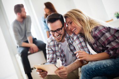 Dijital tablet oynayan ve bakan genç mutlu arkadaşlar