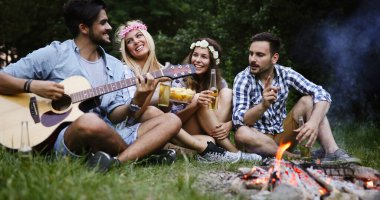 Arkadaşlar şenlik ateşi partisi veriyor ve bira içiyor.