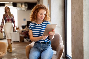 Güzel genç kadın dijital tableti çalışmak, okumak ve sörf yapmak için kullanıyor.