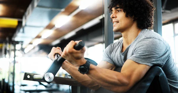 Healthy life and gym exercise concept. Fit young man working out in sport fitness club
