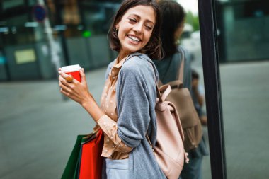Mutlu, genç, güzel bir kadın kahve içer, alışveriş yaptıktan sonra çantalarla gezer..