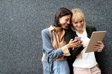 Gülümseyen genç bayan arkadaşlar tabletle eğleniyorlar.