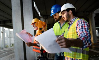 İnşaat mühendisleri ve mimarlardan oluşan bir ekip inşaat alanında çalışıyor.
