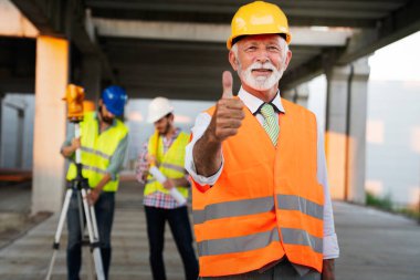 İnşaat mühendisleri ve mimarlardan oluşan bir ekip inşaat alanında çalışıyor.