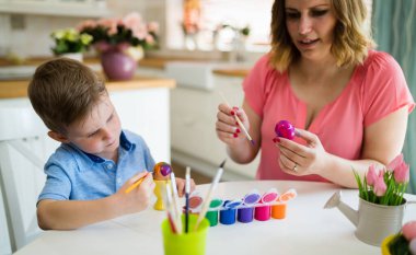 Anne ve çocuk paskalya süslemesi yapıyor ve yumurta boyuyor.