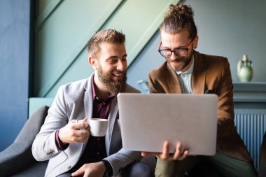 Toplantıda dijital cihazlar kullanan mutlu genç iş adamlarının portresi