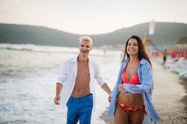 Mutlu mutlu çift gün batımında tropik bir plajda eğleniyor. Romantik tatil kavramı