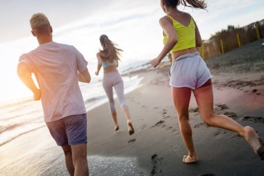 Bir grup sporcu sahilde koşuyor.