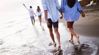 Bir grup arkadaş plajda koşuyor ve yaz tatilinin tadını çıkarıyorlar.