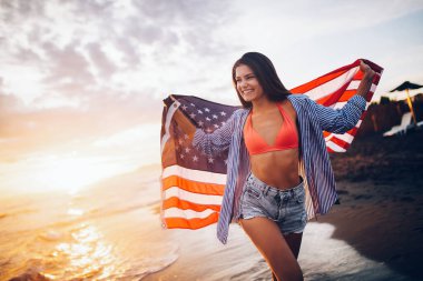 Mutlu kadın gülümseyip plajda koşarken bağımsızlık gününü kutluyor ve Amerika 'da özgürlüğün tadını çıkarıyor.