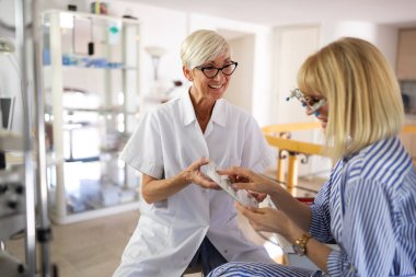 Gözlükçü kliniğinde görme testi yaptıran mutlu genç bir kadın.