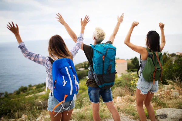 Hiking with friends is so fun. Group of young people with backpacks walking together by the road