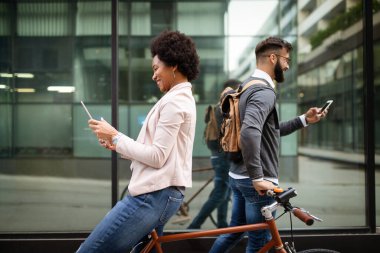 Şehirdeki teknoloji cihazlarını kullanan mutlu, çeşitli insanlar.
