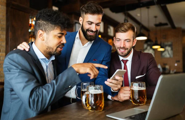 Business people drink beer after work. Businessmen enjoy a beer at a pub