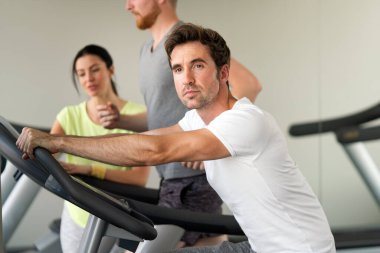 Spor salonunda koşu bandında egzersiz yapan bir grup arkadaş.