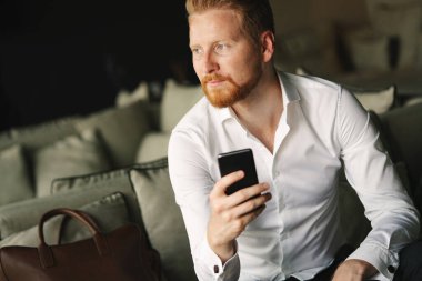 Akıllı telefonunu kullanan mutlu genç bir adam.