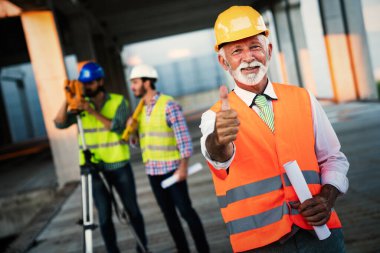 İnşaat mühendisleri ve mimarlardan oluşan bir ekip inşaat alanında çalışıyor.