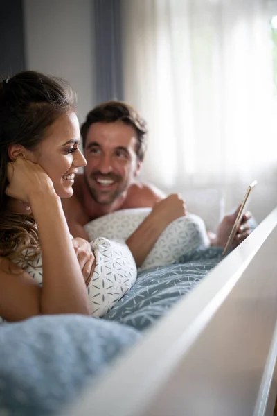 Couple Joyeux Regardant Une Tablette Ensemble Riant Tout Étant Couché — Photo