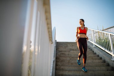 Portrait of healthy cheerful woman pausing after a run in a city