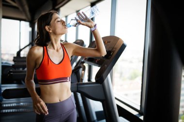 Antrenmandan sonra ferahlatıcı. Spor salonunda susuz kalmamak için su içen güzel genç bir kadın.