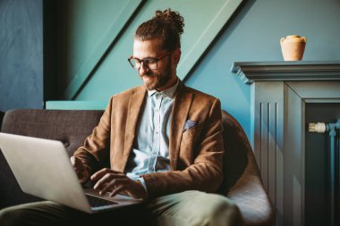 İş yerinde dizüstü bilgisayarda başarılı genç ve yakışıklı bir işadamı.
