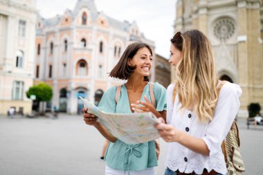 Turistlerin elinde haritayla gezdiği mutlu gezgin kadınlar.