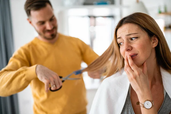 Man makes haircut to woman at home during quarantine. Isolation, couple, haircut concept.