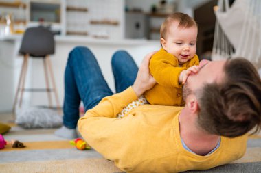 Sevecen baba ve küçük kızı evde oynaşıp kaynaşıyorlar.
