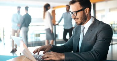 Ofiste bilgisayar üzerinde çalışan genç yakışıklı işadamı