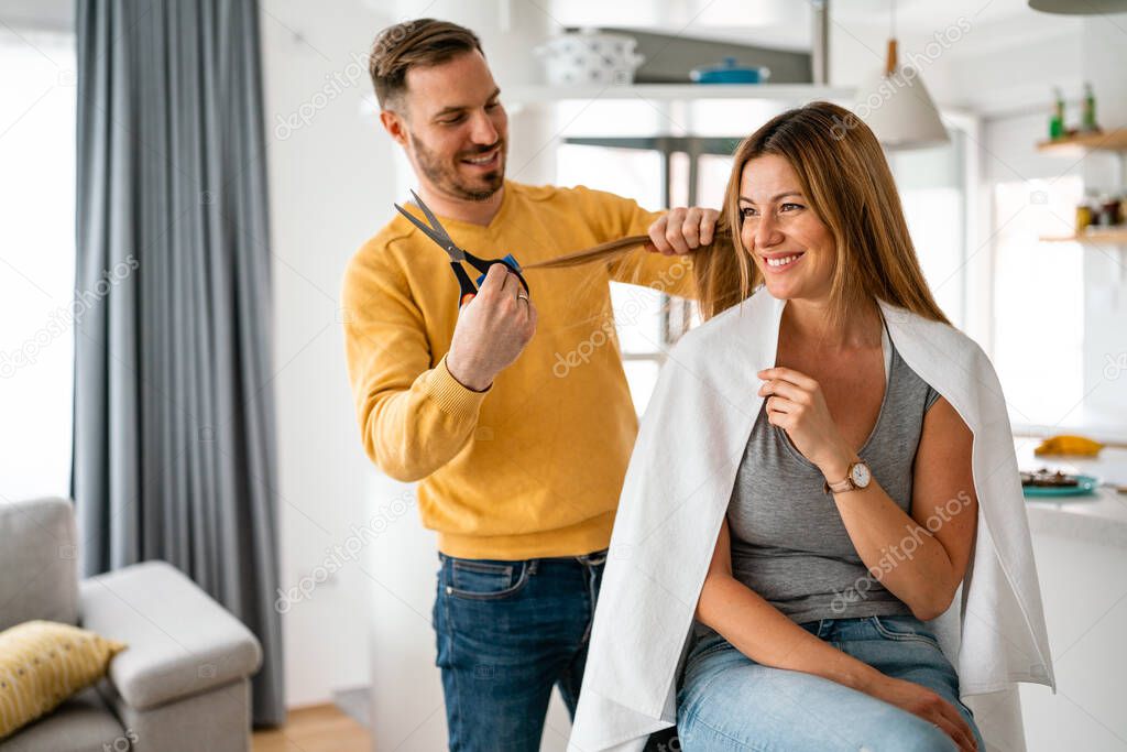 Couple having hair cut at home during isolation coronavirus pandemic, online hairdressing learning on a tablet