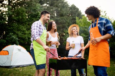 Arkadaşlar doğada barbekü yaparken eğleniyorlar.