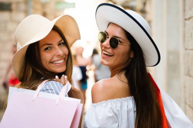 Güzel alışveriş kadınları alışveriş torbalarını tutarken ve yaz tatilinde eğlenirken mutlu olurlar.