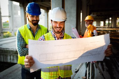 İnşaat mühendisleri ve mimarlardan oluşan bir ekip inşaat alanında çalışıyor.