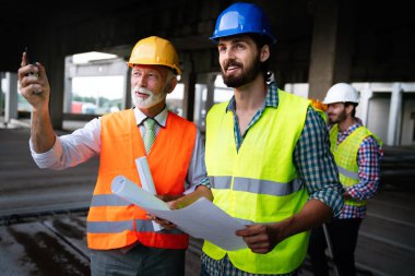 İnşaat mühendisleri ve mimarlardan oluşan bir ekip inşaat alanında çalışıyor.