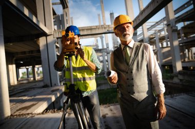 İnşaat alanı kontrol belgeleri ve iş akışı üzerine grup halinde çalışan mimarlar ve mühendisler.