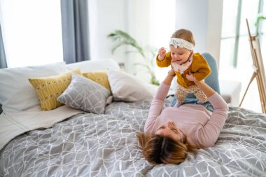 Anne ve bebek evde oynayıp gülümsüyor. Mutlu aile.