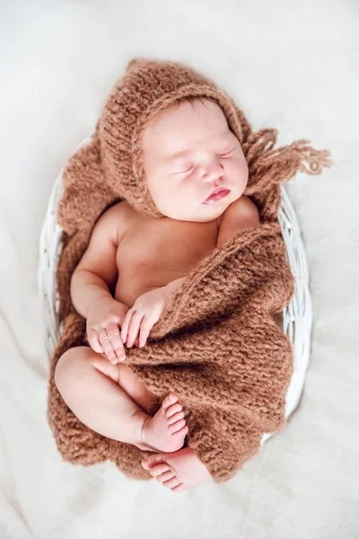 Pasgeboren baby in gebreide cap en een deken in een mandje. — Stockfoto