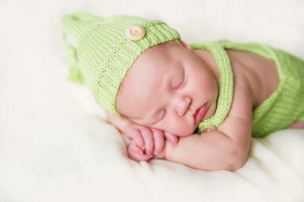 Νεογέννητο μωρό σε μια πράσινη ολόσωμη φόρμα και καπέλο. — Φωτογραφία Αρχείου