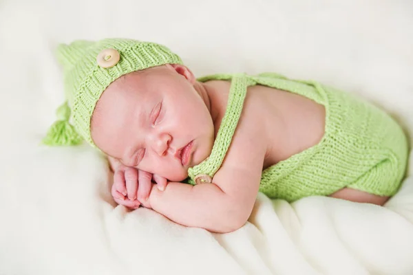 Νεογέννητο μωρό σε μια πράσινη ολόσωμη φόρμα και καπέλο. — Φωτογραφία Αρχείου