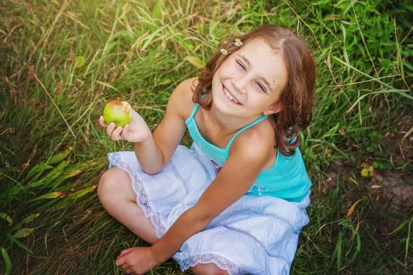 Menina com uma maçã no fundo do jardim de verão — Fotografia de Stock