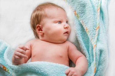 Yeni doğan bebek yalan etrafa bir havlu ile kaplı.