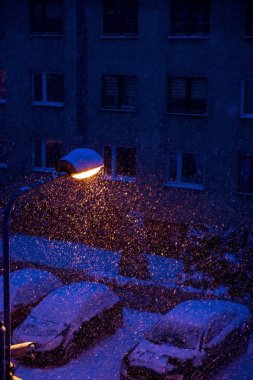 Bir kış akşamı sokakta bir fener ışığında yağan kar.