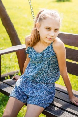 Yaz bahçesinde bir bankta oturan bebek kız.