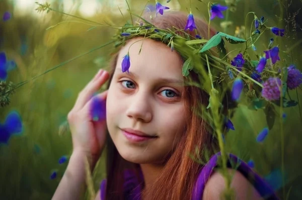 彼女の頭の上に花の花輪を持つ草に座っている子供の女の子 — ストック写真