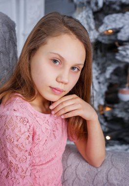 Noel ağacının yanındaki koltukta kız çocuk.