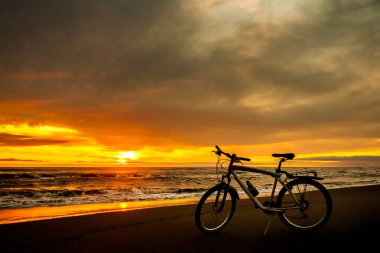 Turist Bisiklet günbatımı zaman Denizi'nin kıyısında