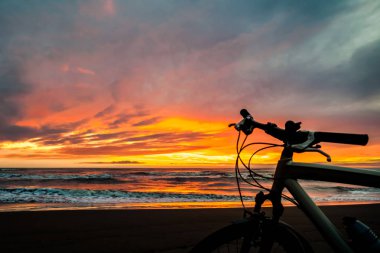 Turist Bisiklet günbatımı zaman Denizi'nin kıyısında