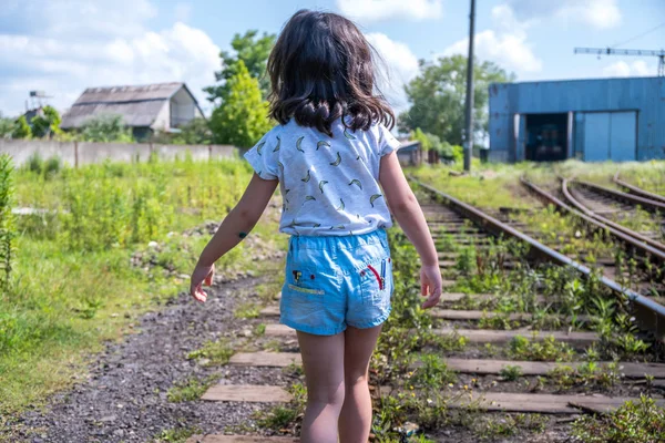 Liten flicka gå på räls, tillbaka till en kamera — Stockfoto