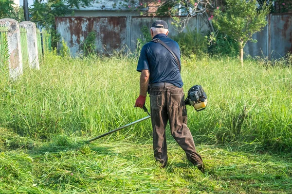 O jardineiro cortando grama por cortador de grama — Fotografia de Stock