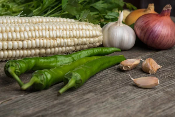 Цибуля, кукурудза, часник, перець, коріандр і петрушка на старому гуті — стокове фото